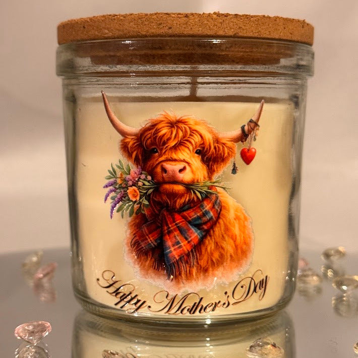 Glass candle jar with a highland cow illustration and 'Happy Mother's Day' text on a reflective surface.